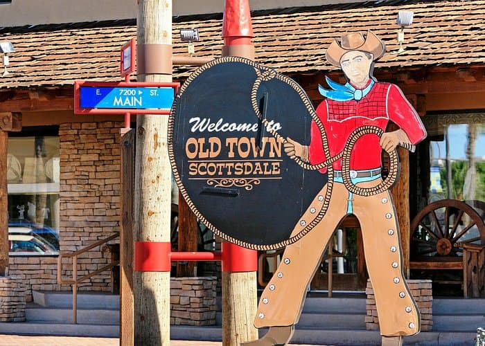 Colorful cowboy cutout sign with a lasso welcoming visitors to Old Town Scottsdale, Arizona.